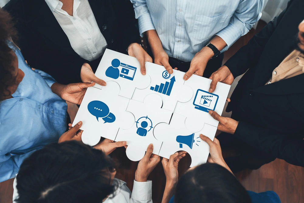 Equipa de profissionais a unir peças de puzzle com ícones de marketing digital, simbolizando colaboração e estratégia integrada