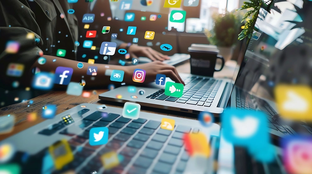 Pessoa a trabalhar em portátil rodeada de ícones de redes sociais, representando gestão de redes sociais para empresas