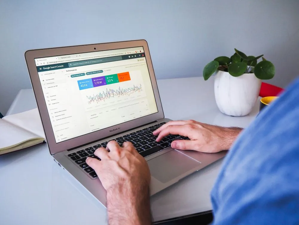 Profissional a analisar métricas de desempenho SEO no Google Search Console através de computador portátil