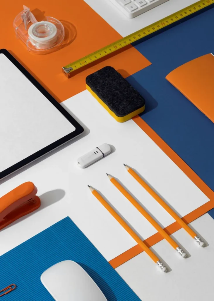 Vista de cima de materiais de escritório organizados, incluindo lápis, fita adesiva e régua, representando design e criatividade